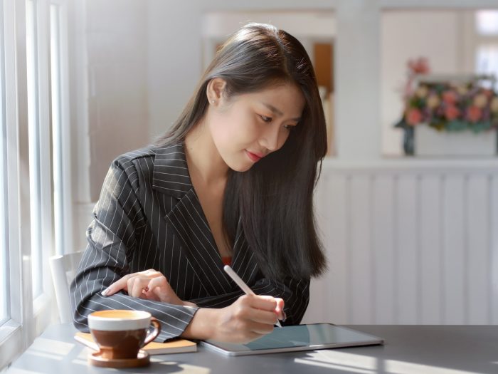 woman-in-gray-and-white-pinstripe-dress-shirt-using-black-3815624