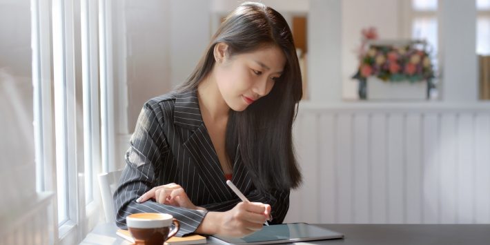 woman-in-gray-and-white-pinstripe-dress-shirt-using-black-3815624